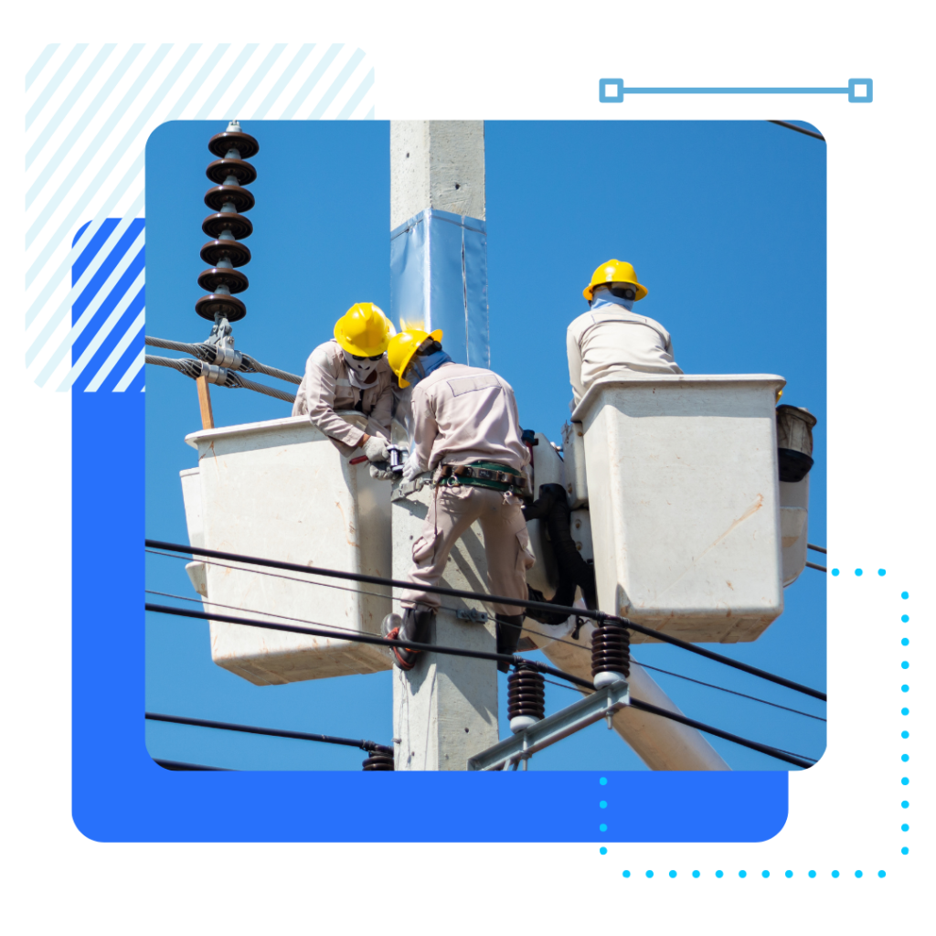 Three utility workers in yellow helmets and safety gear work atop a power pole.
