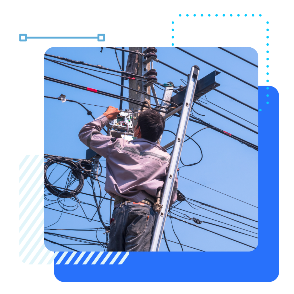 A worker on a ladder repairs electrical wires on a utility pole against a clear blue sky.