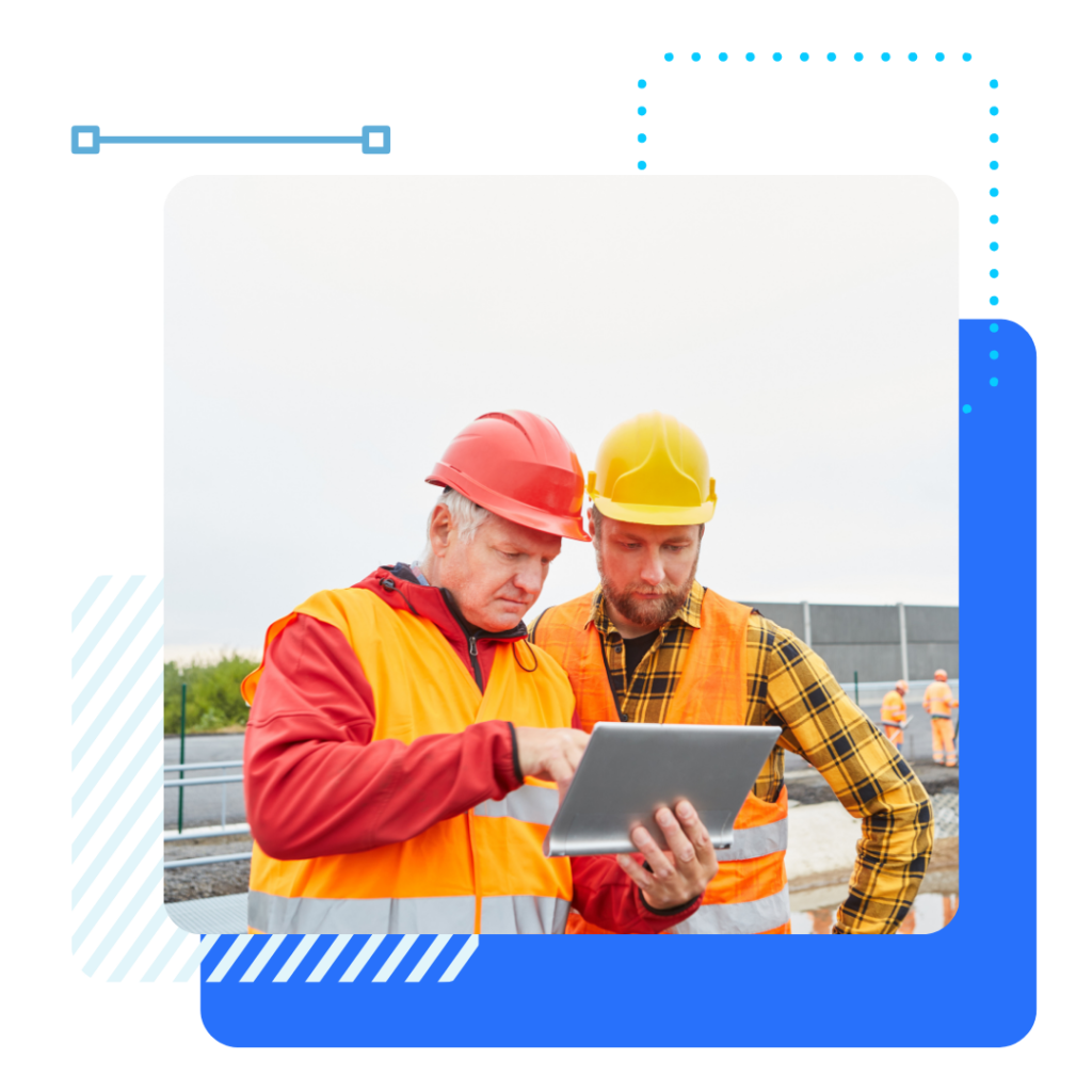 Two construction workers in safety vests and helmets focus on a tablet at a worksite. The image conveys teamwork and modern technology use.