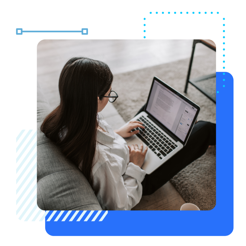 An insurance woman in a white shirt and glasses sits on a sofa, using a laptop on her lap.