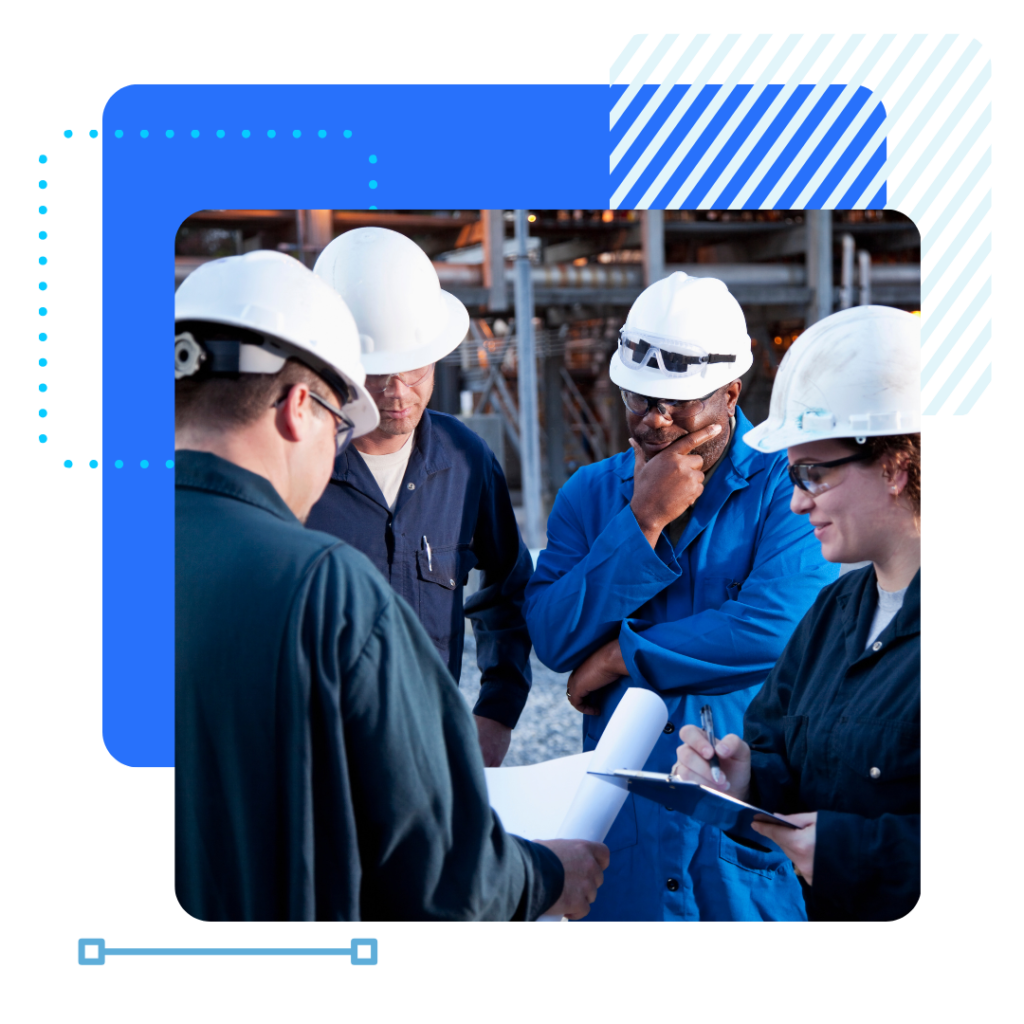 A group of manufacturers in hard hats and overalls having a discussion on a manufacturing site.