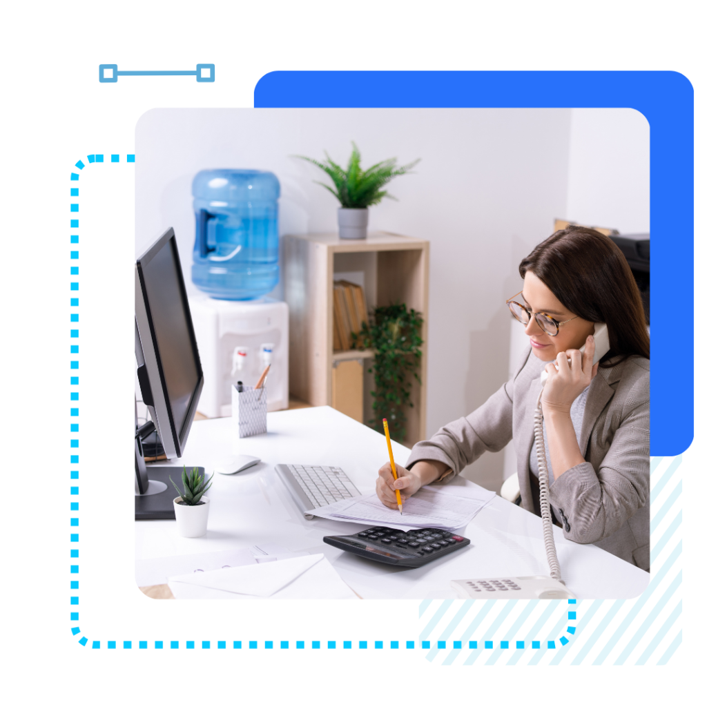 A woman in glasses sits at a desk, talking on a landline phone and writing with a pencil. The office has a water cooler and a potted plant.